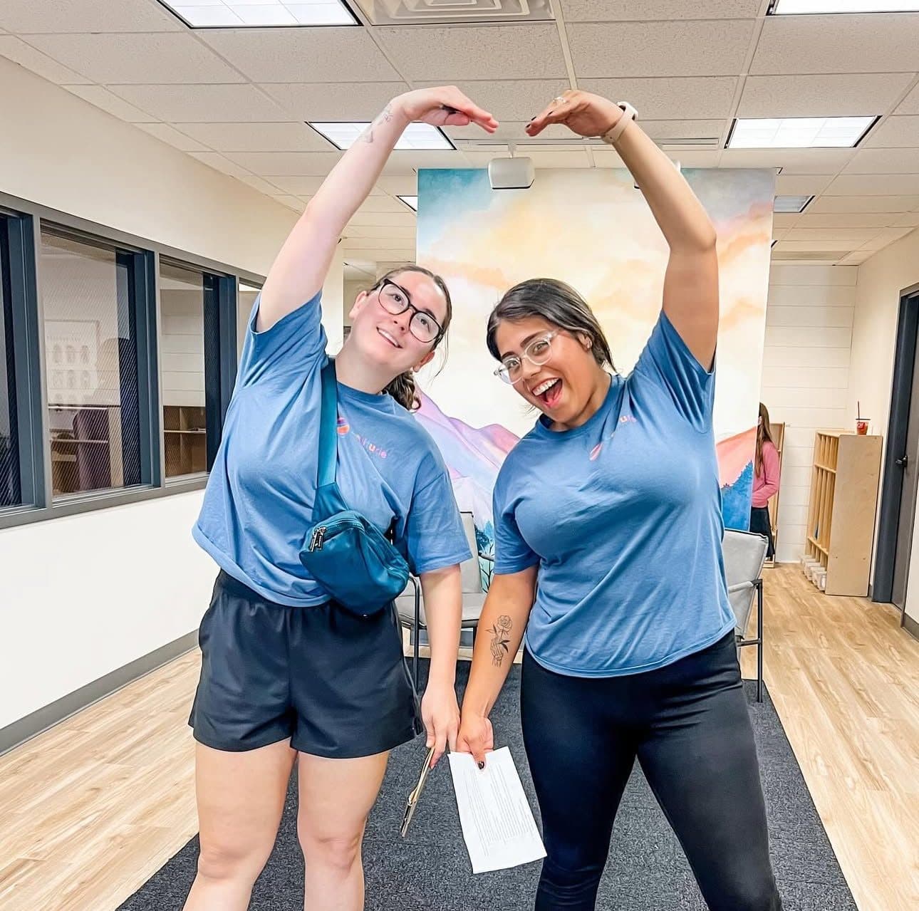 Two Latitude Therapy team members making a heart shape with their arms