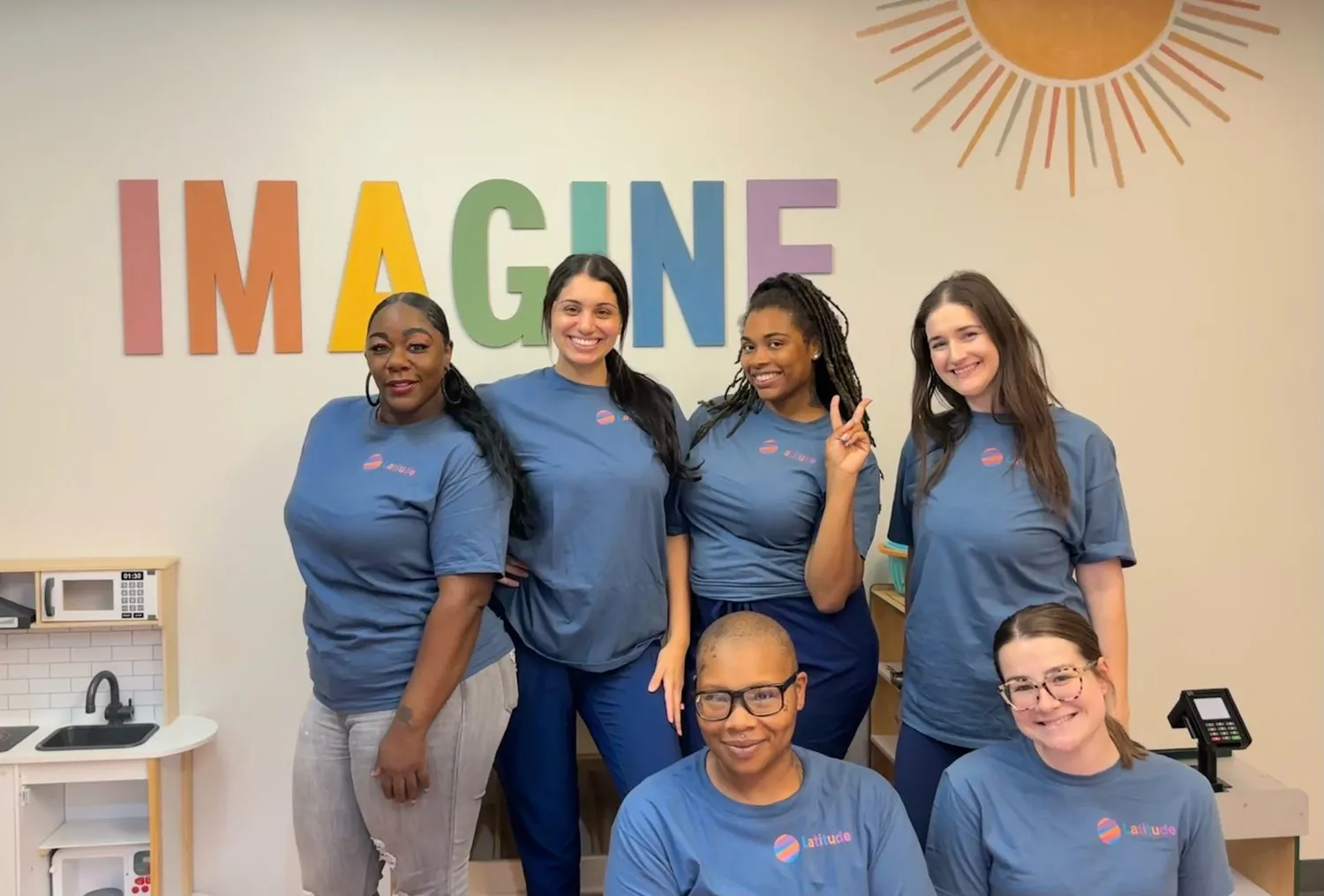 Six Latitude Therapy team members in front of the Imagine wall at the Bridgeton center